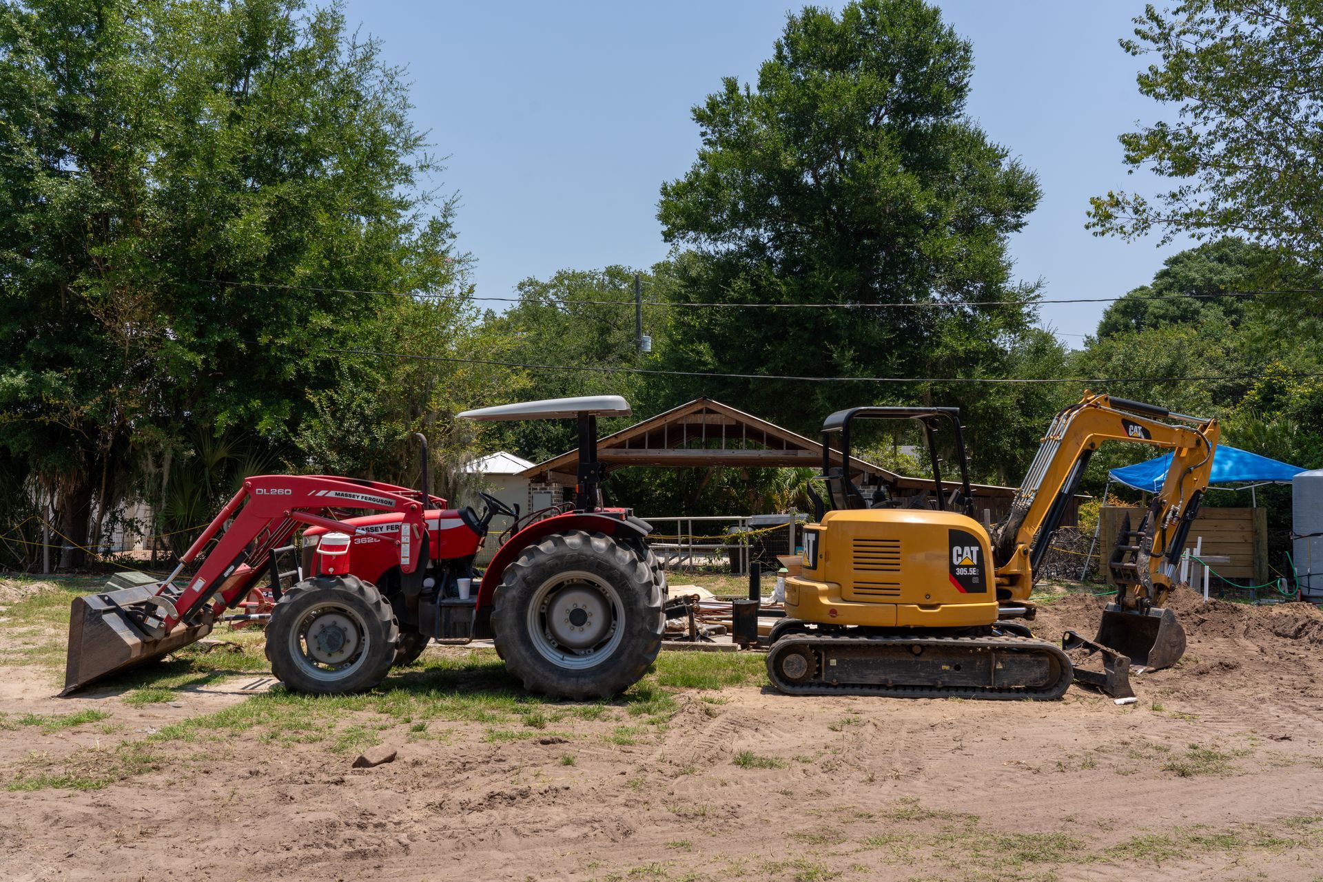 a red massey ferguson tractor is parked next to a yellow cat excavator