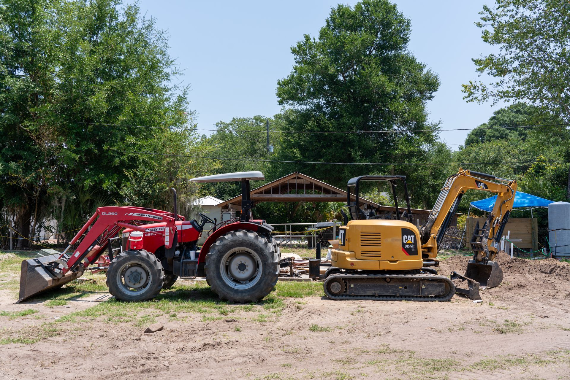 a cat excavator sits next to a massey ferguson tractor