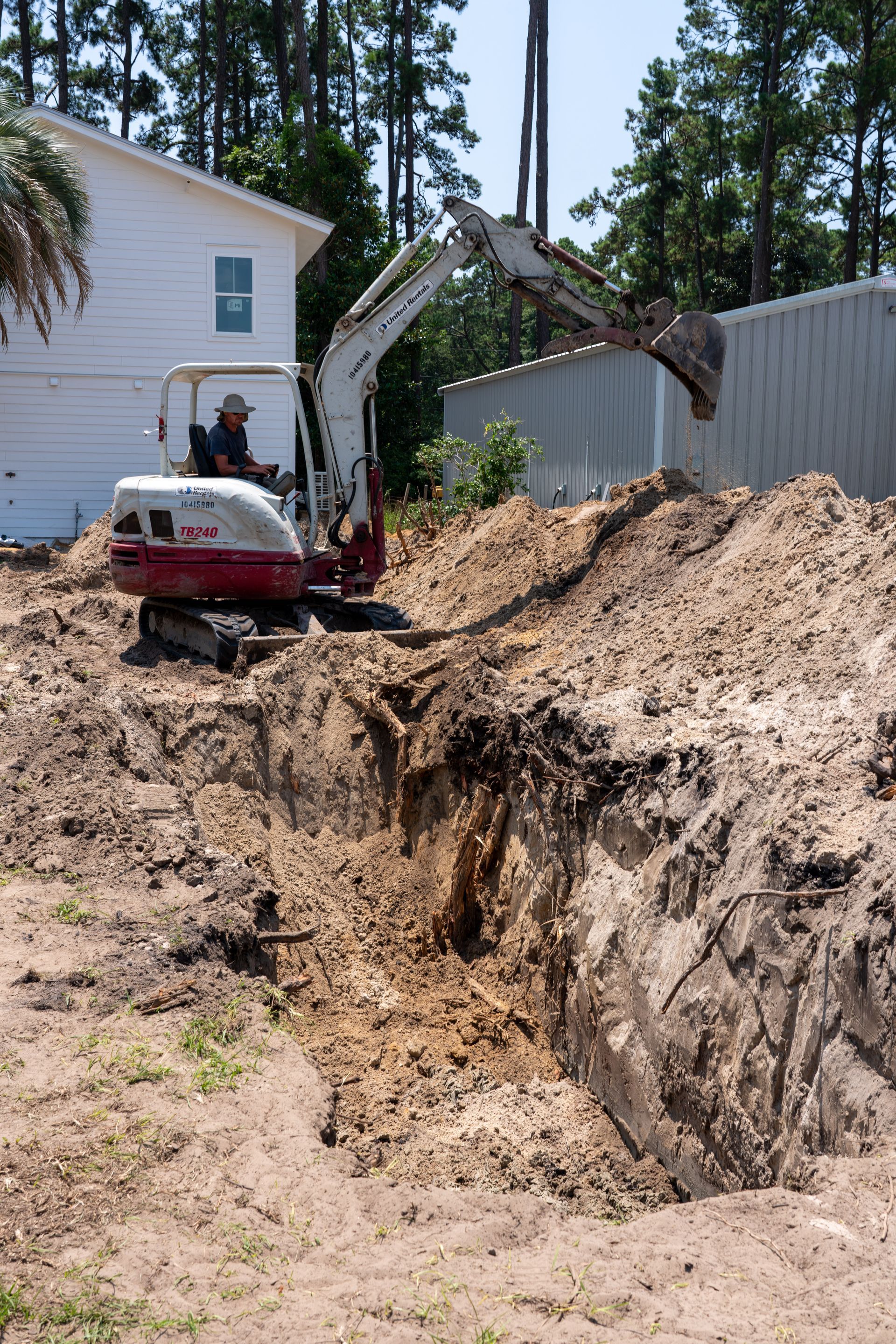 a man is driving a white and red excavator that says tb240