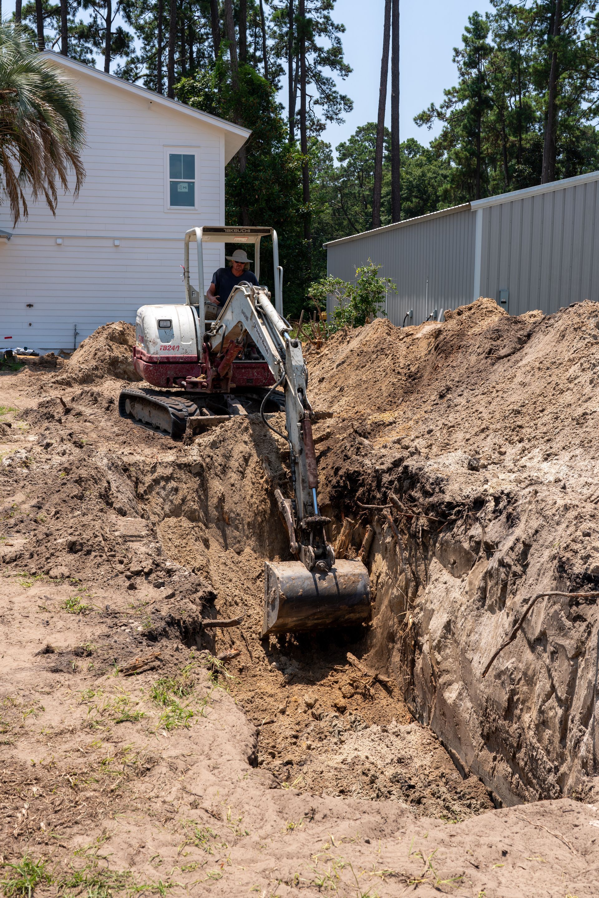 a man is driving a white and red excavator that says takeuchi