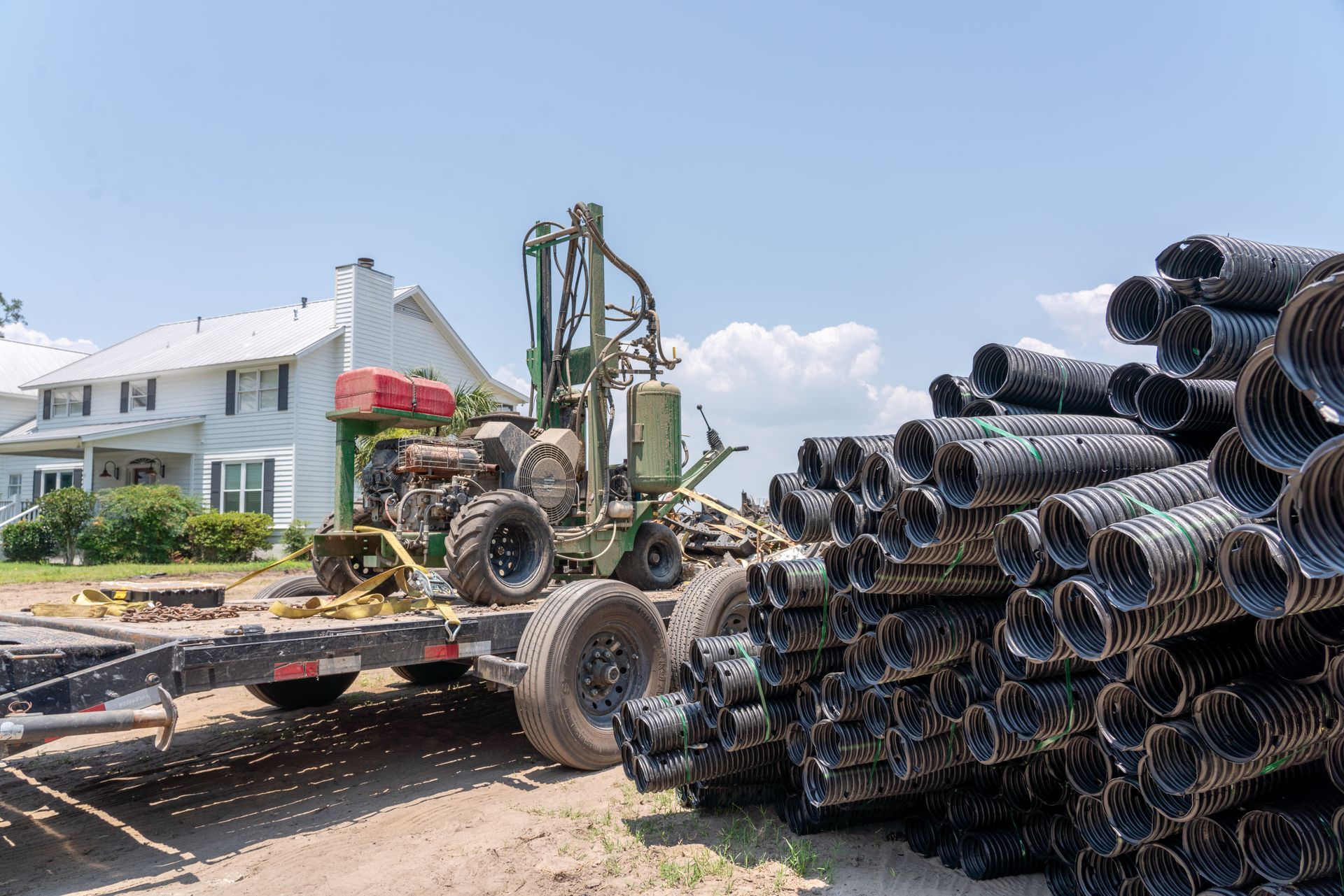 a stack of pipes sits on a trailer in front of a house