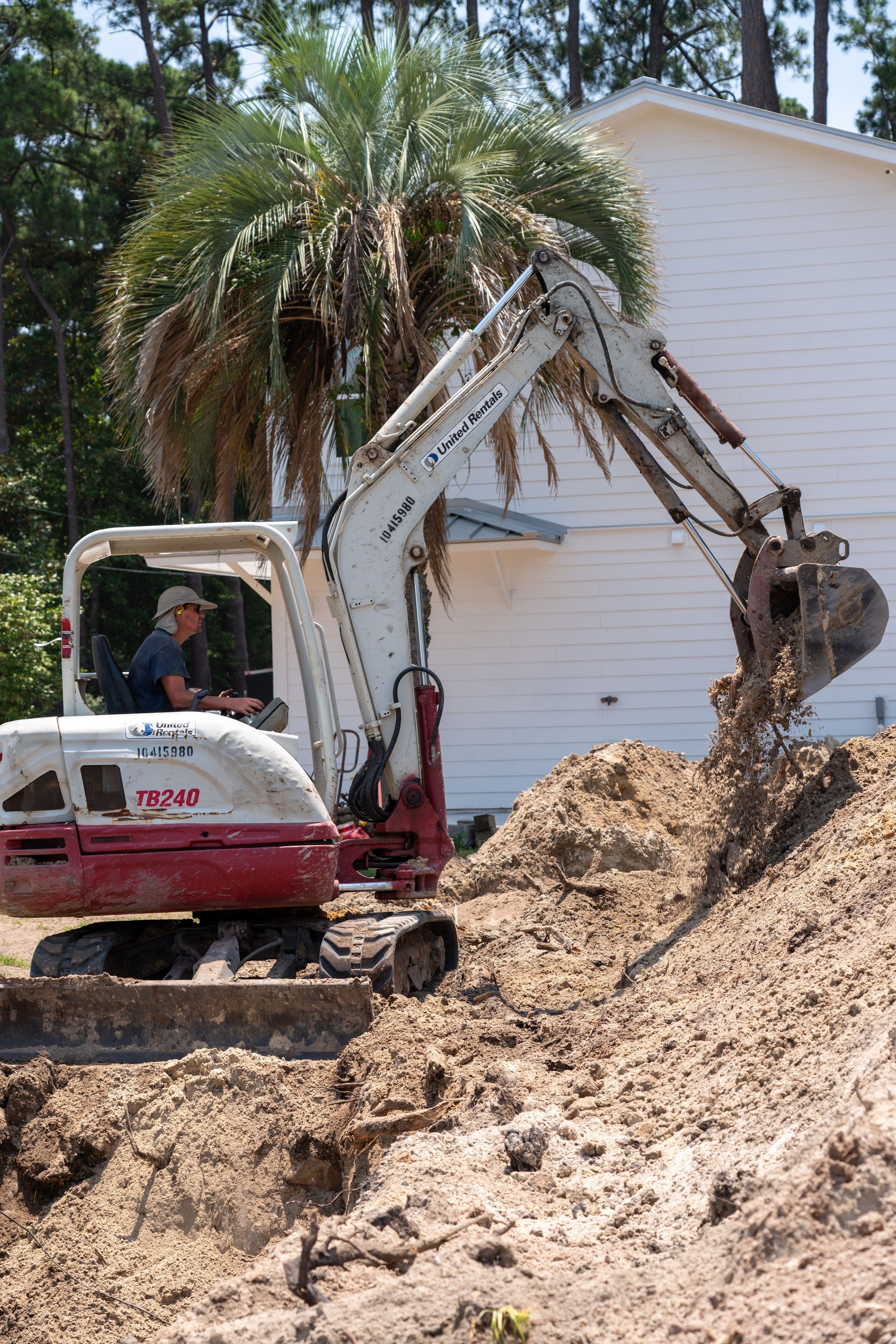 a man driving a white and red excavator that says tb240