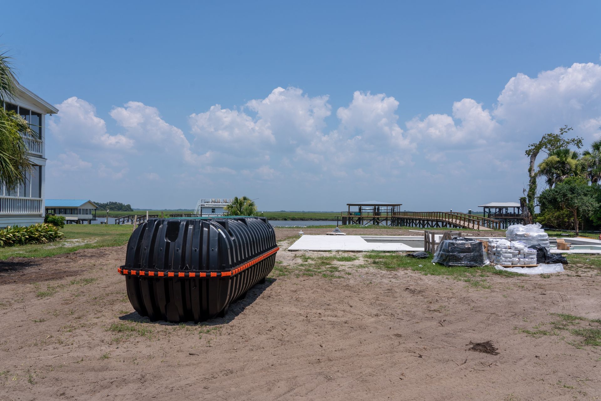 a large black tank with orange trim sits in a dirt field