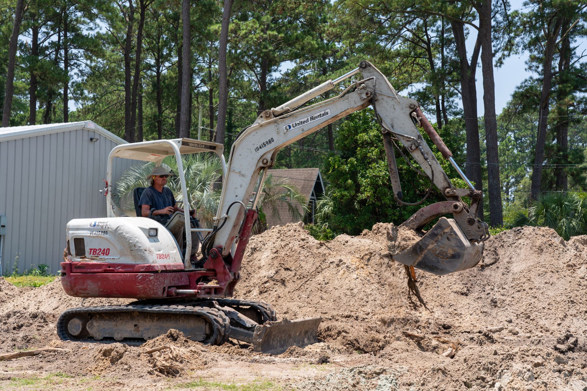 a man is driving a white and red excavator that says crown rentals
