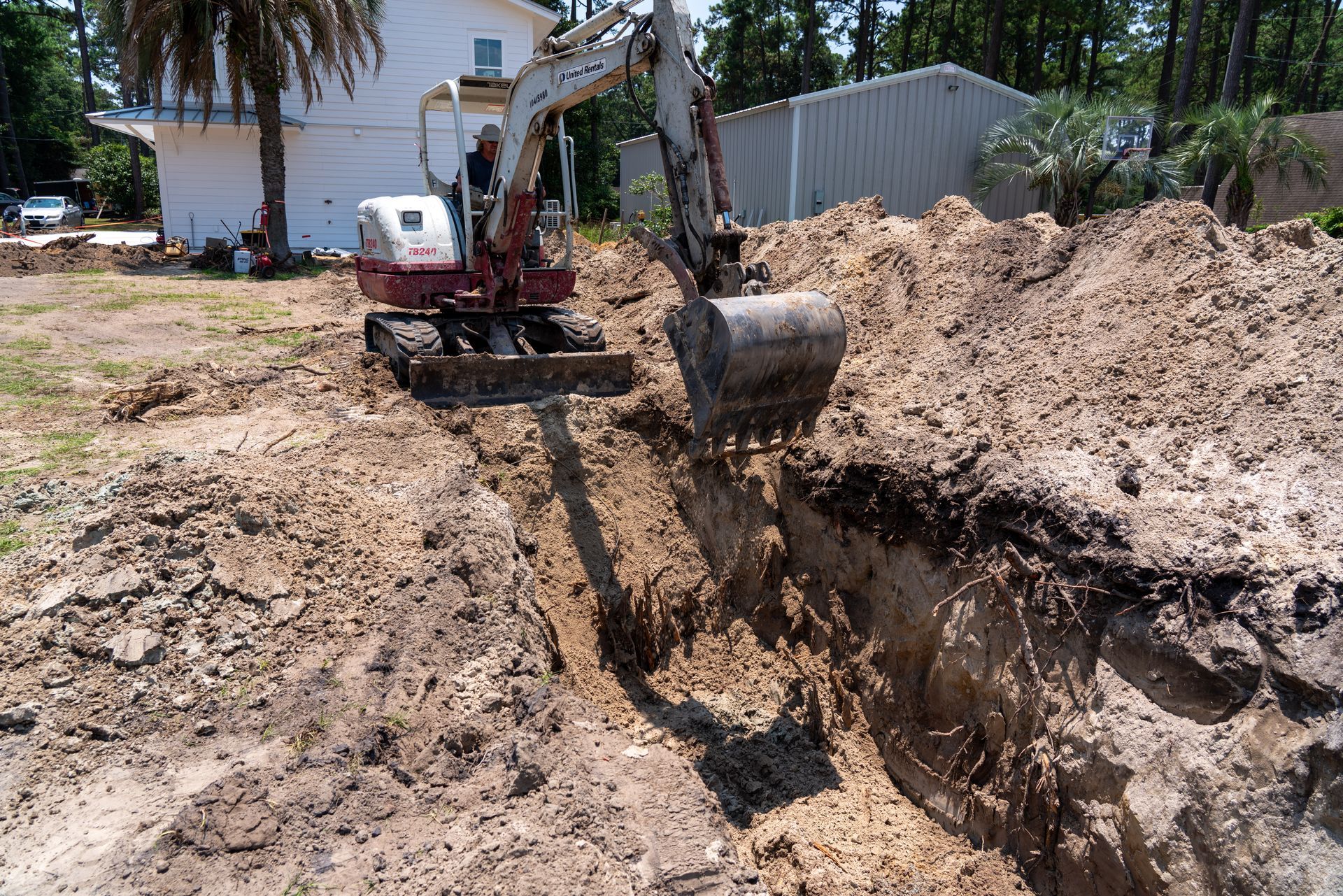 a red and white excavator is digging a hole in the dirt
