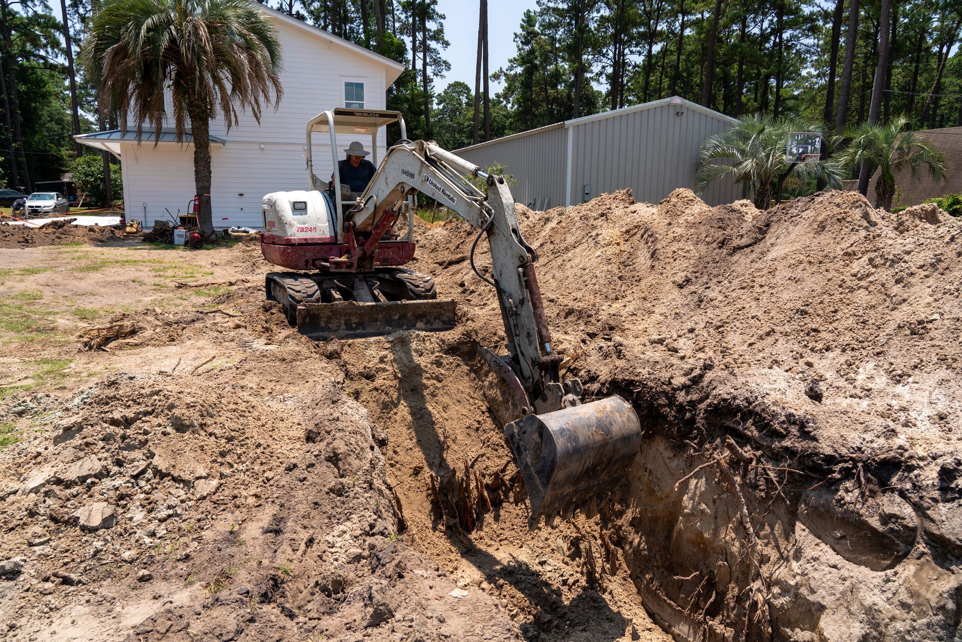 a man is driving a red and white excavator that says takeuchi