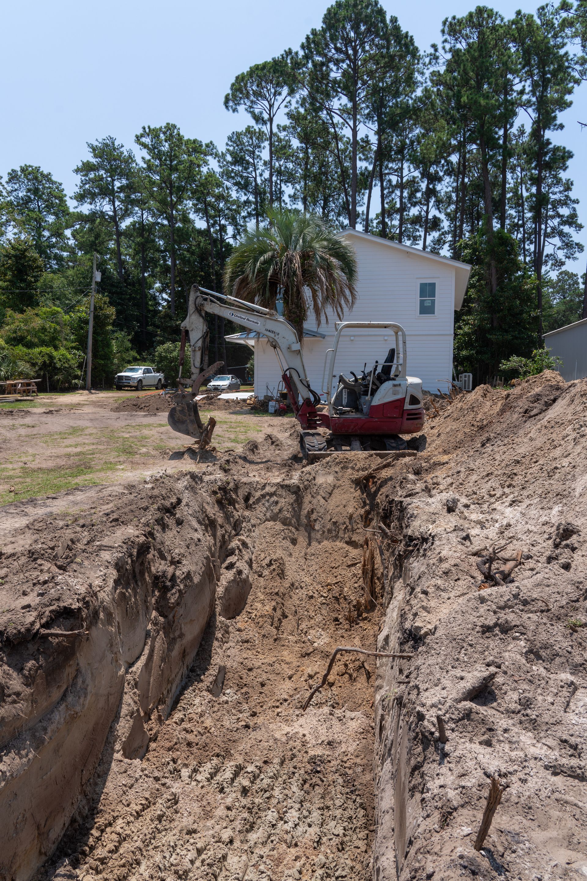 an excavator is digging a hole in the dirt in front of a house