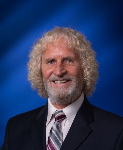 A woman is sitting at a desk with a laptop and a vase of flowers.