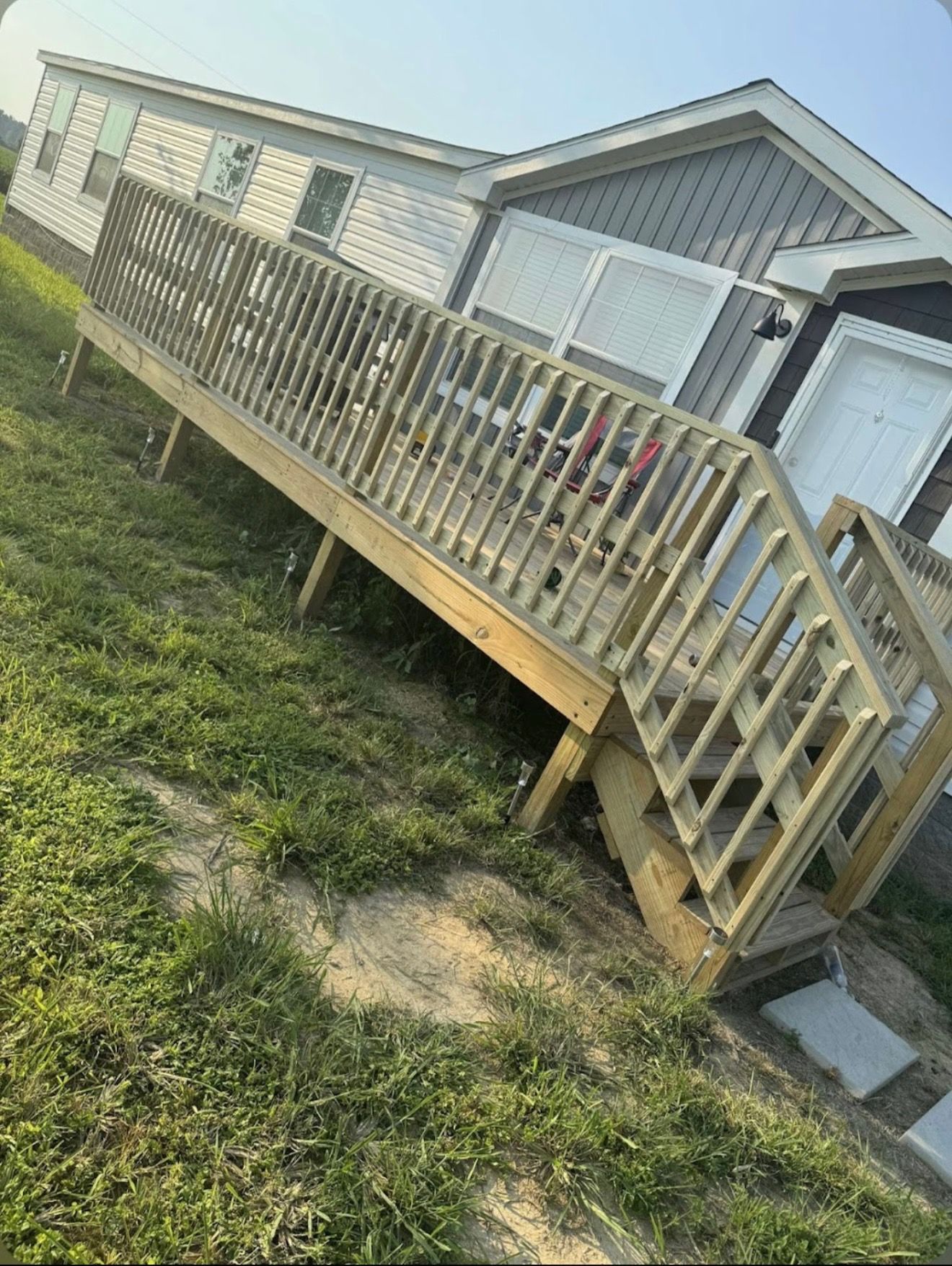 A mobile home with a wooden deck and stairs in front of it.