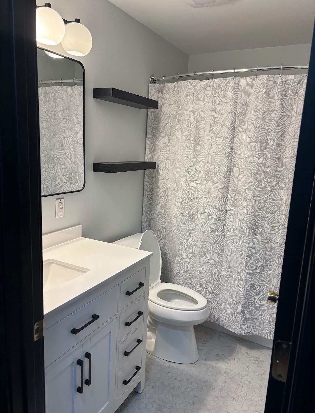 A bathroom with a sink , mirror and shower stall.