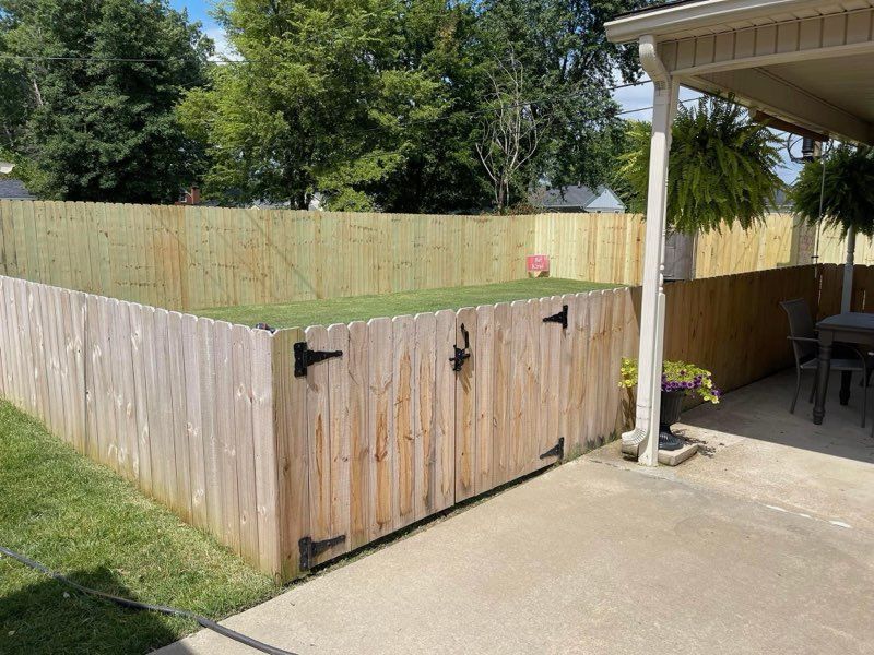 A wooden fence surrounds a patio with a table and chairs.