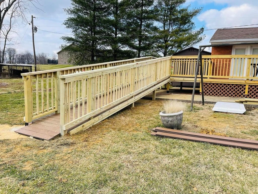 A wooden ramp leading to a deck next to a house.