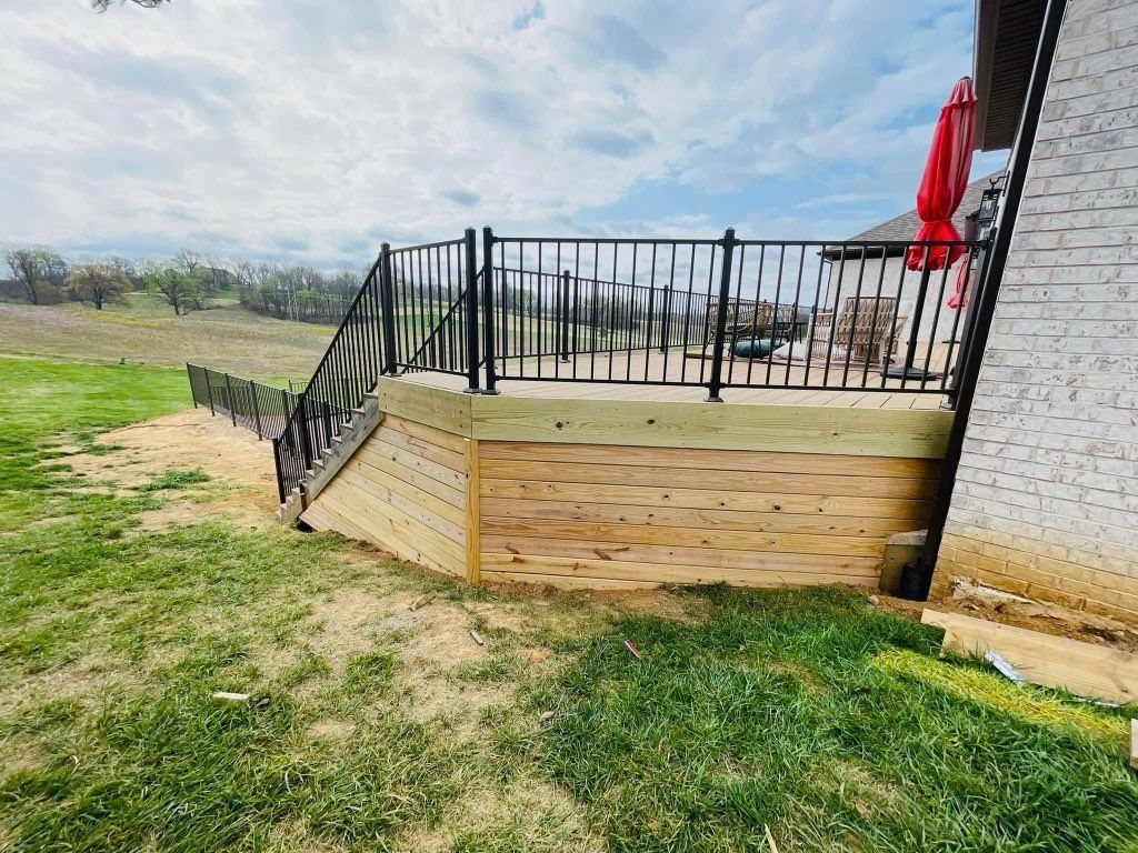A wooden deck with a metal railing and a slide in the backyard of a house.