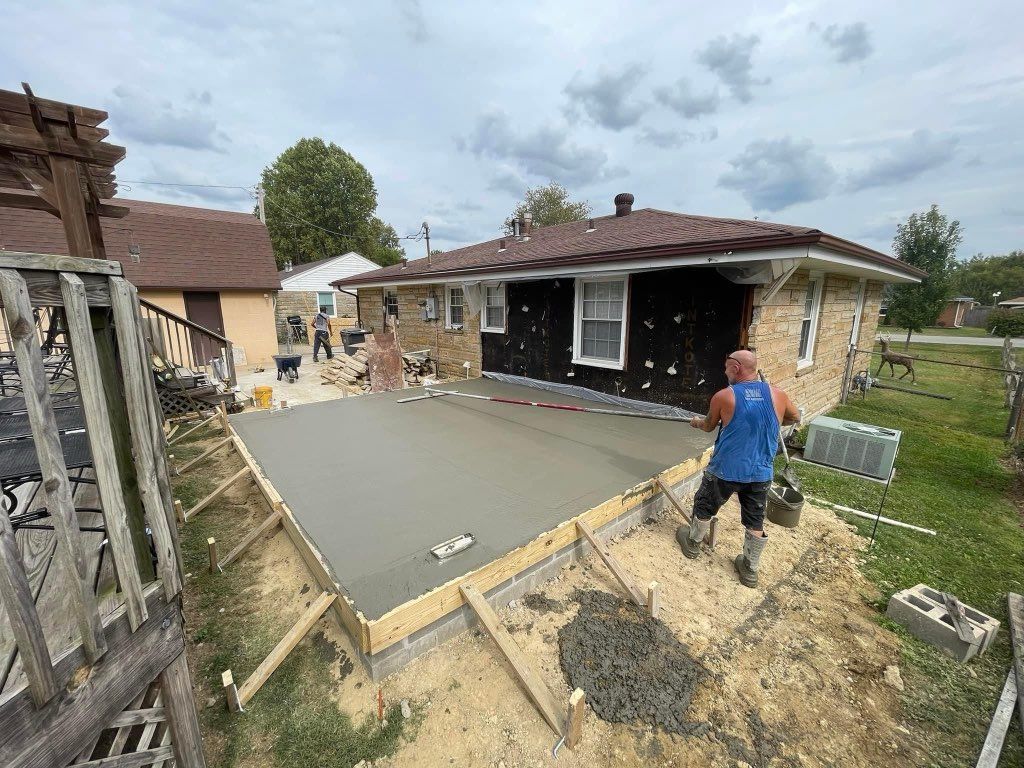 A man is pouring concrete in front of a house.