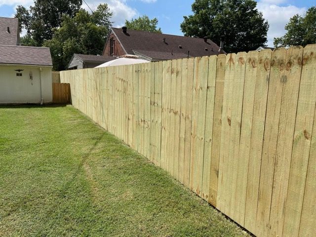 A wooden fence is in the backyard of a house.