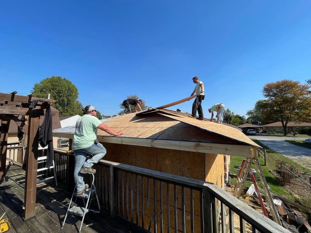 A group of men are working on the roof of a house.