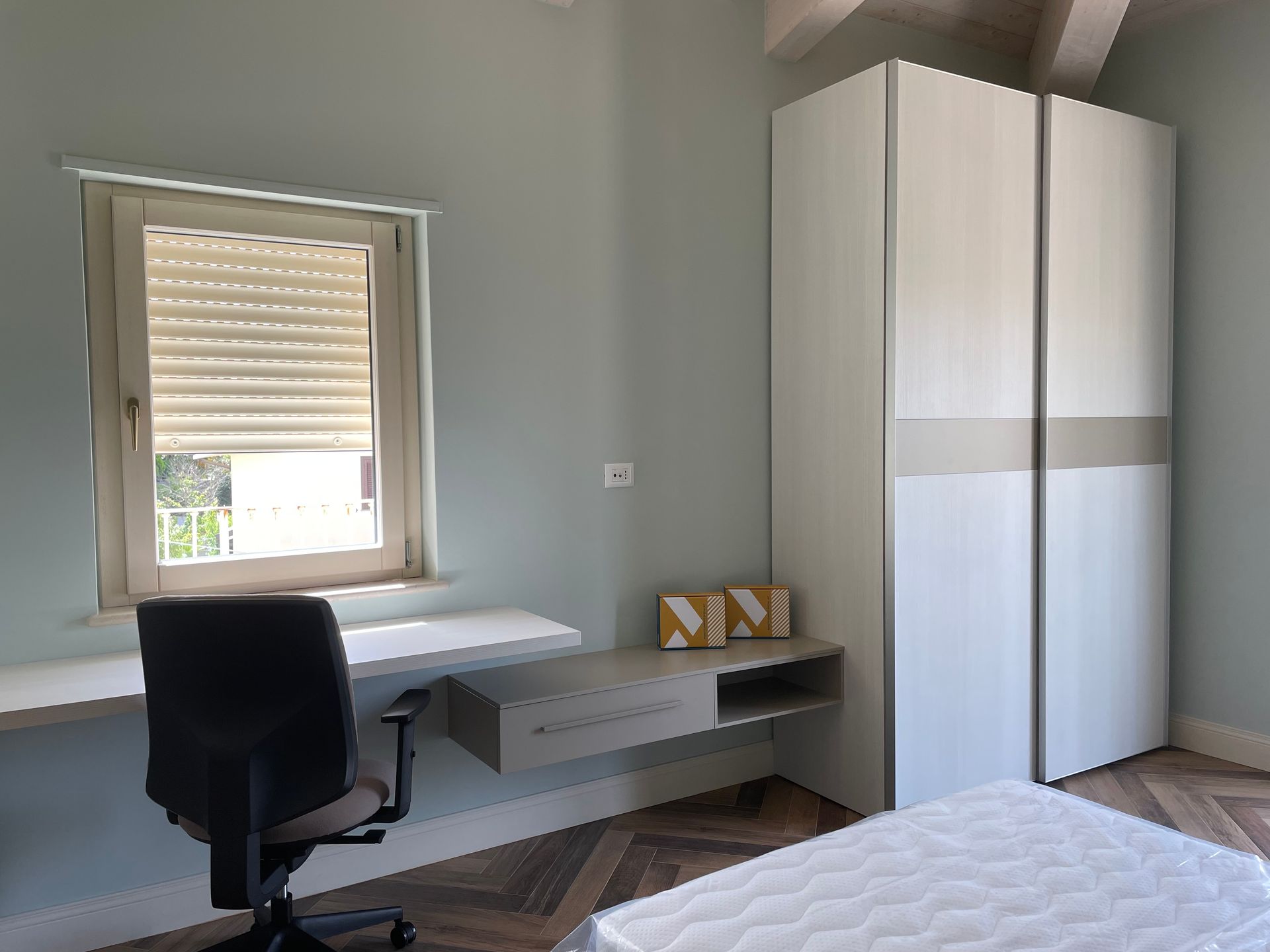 Una camera da letto con letto, scrivania, sedia e armadio.