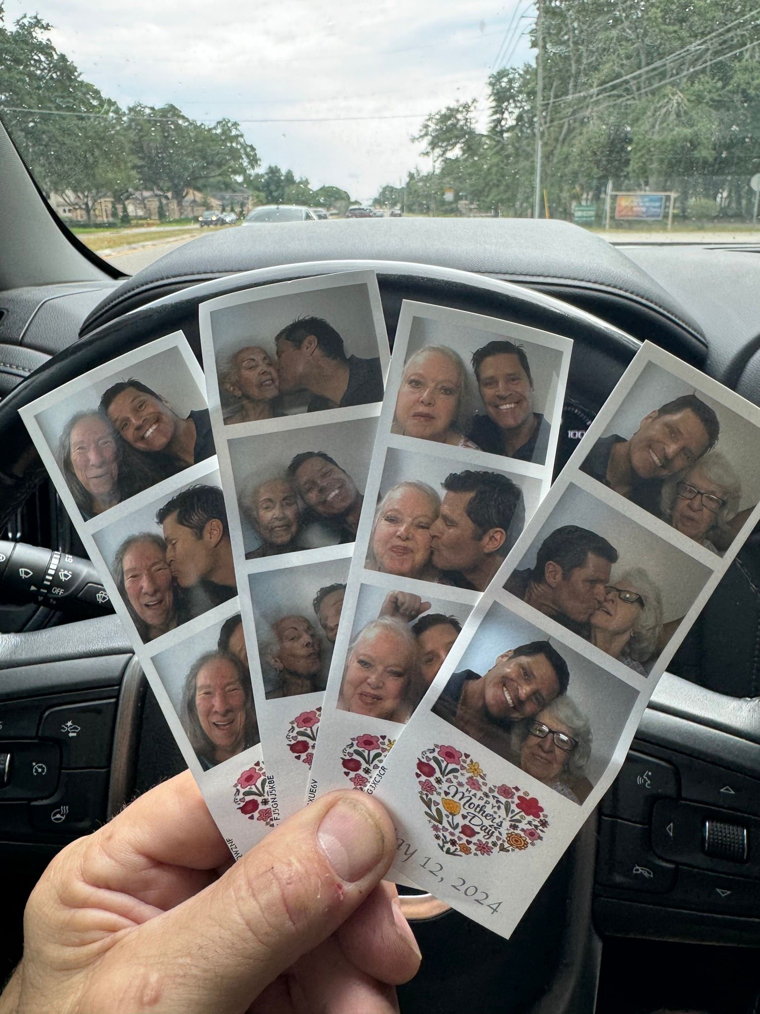 Hand holding photo booth strips with couples kissing and smiling in a car.