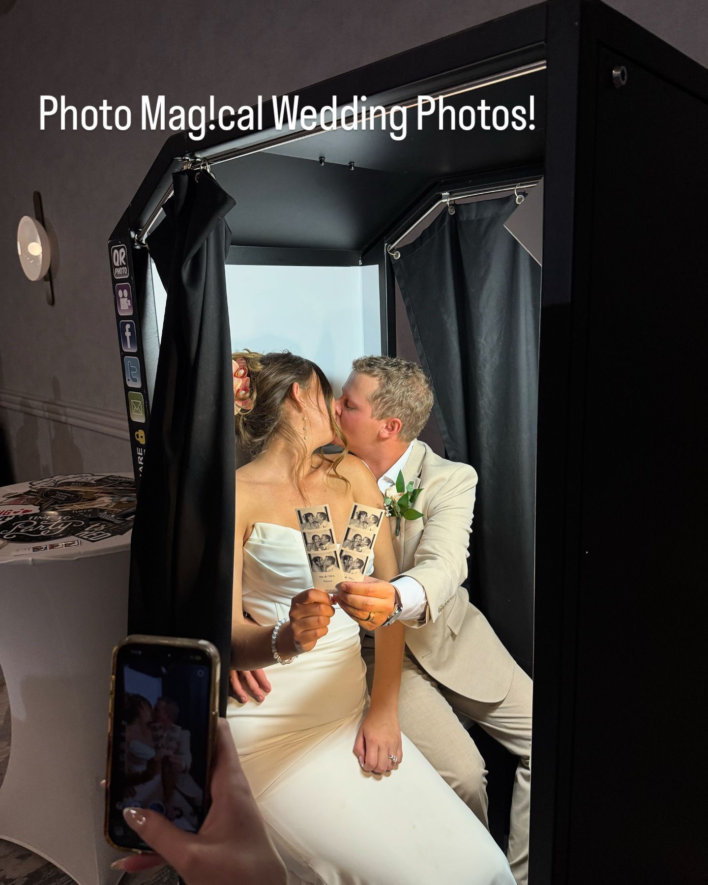 Newlyweds kiss in a photo booth, holding sign: 
