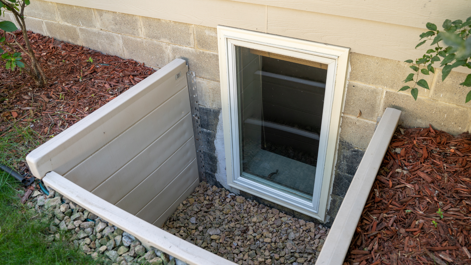 Basement egress window with window well and gravel drainage installed outside a Virginia home