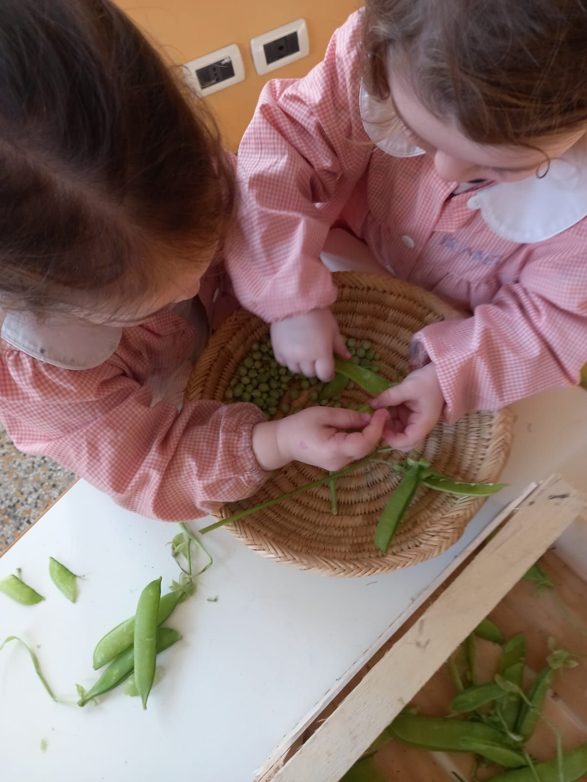 Due bambine stanno giocando con i piselli verdi su un tavolo