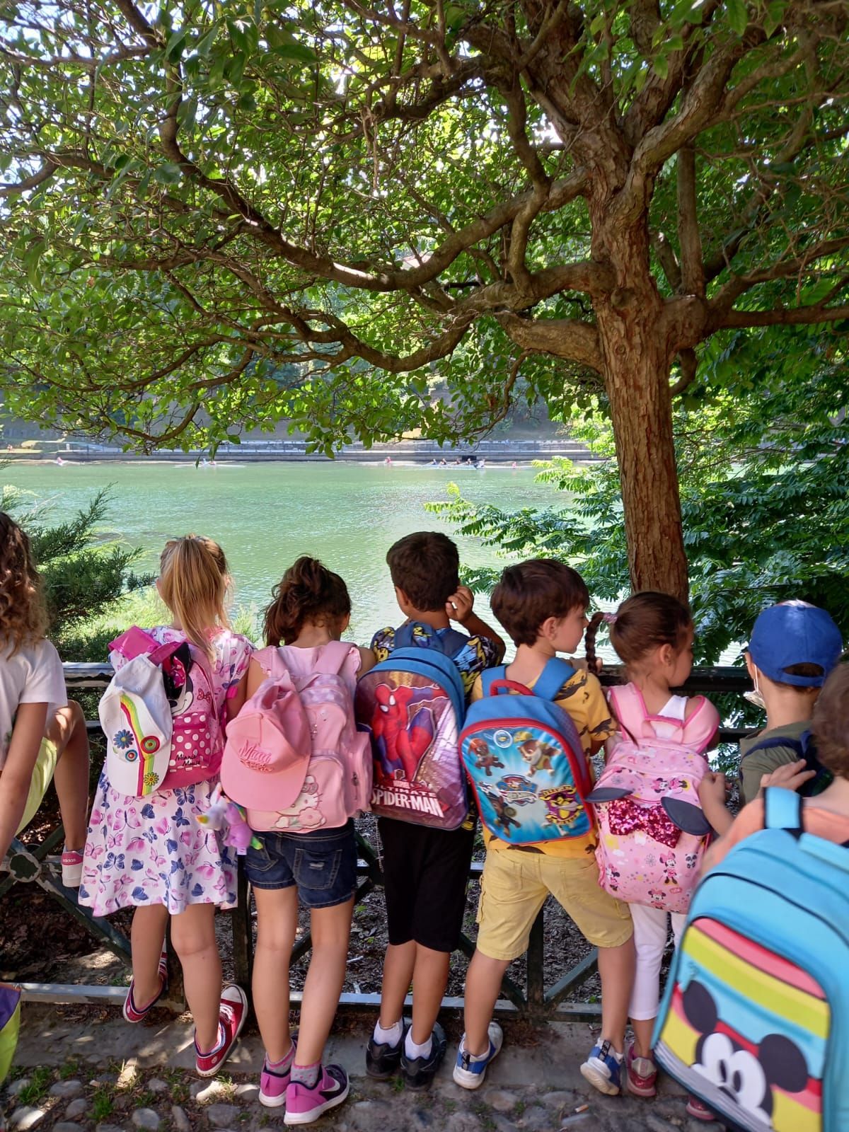 Un gruppo di bambini con zaini che guardano un lago