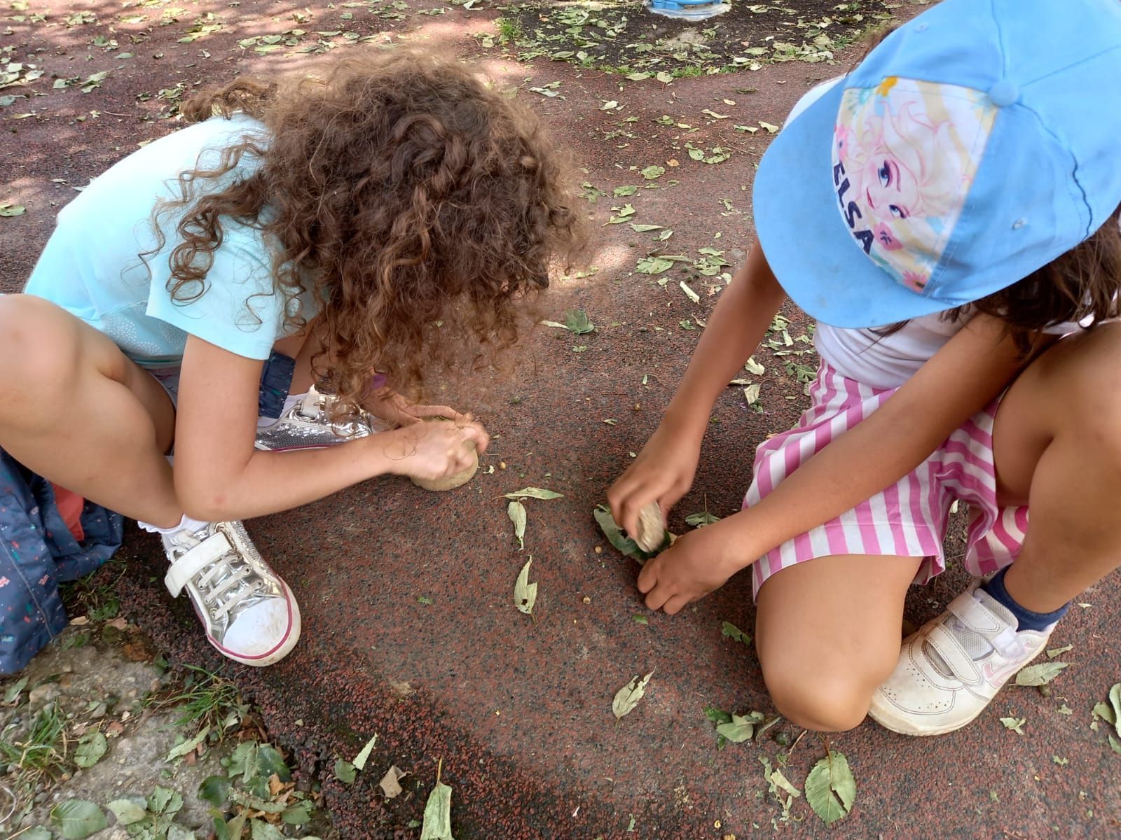 Due bambine stanno giocando con le foglie a terra