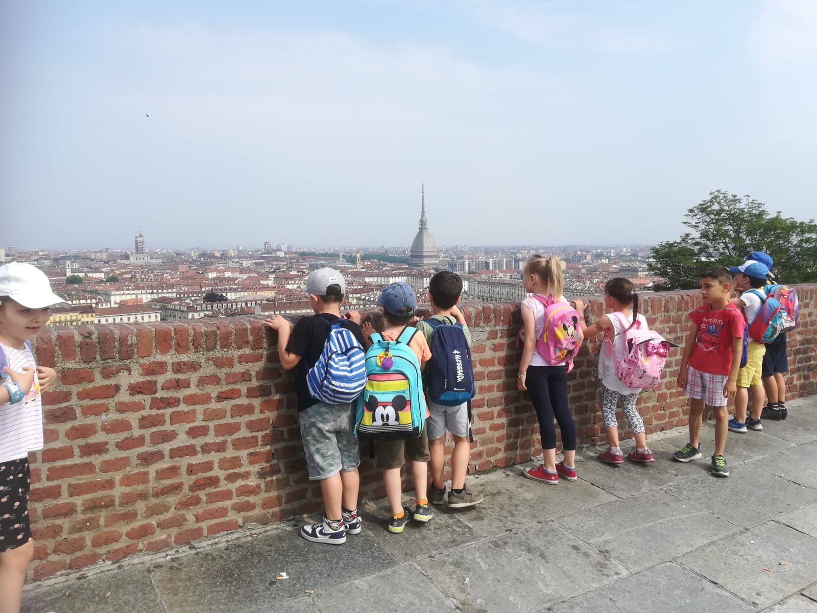 Un gruppo di bambini in piedi accanto a un muro di mattoni che guardano una città.