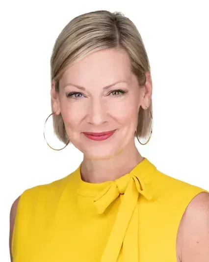 Portrait of a smiling person in a bright yellow blouse with hoop earrings on a white background