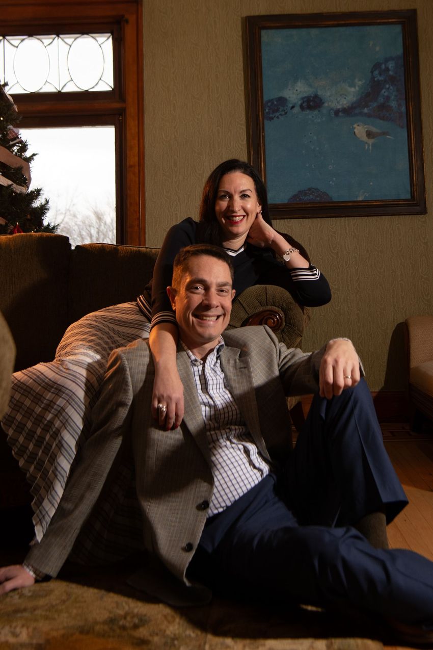 a man and a woman are posing for a picture while sitting on a couch .