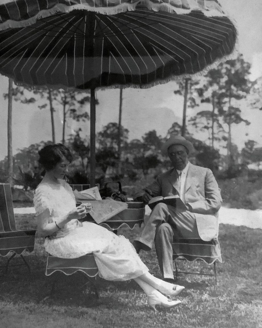 a black and white photo of a man and woman sitting under an umbrella