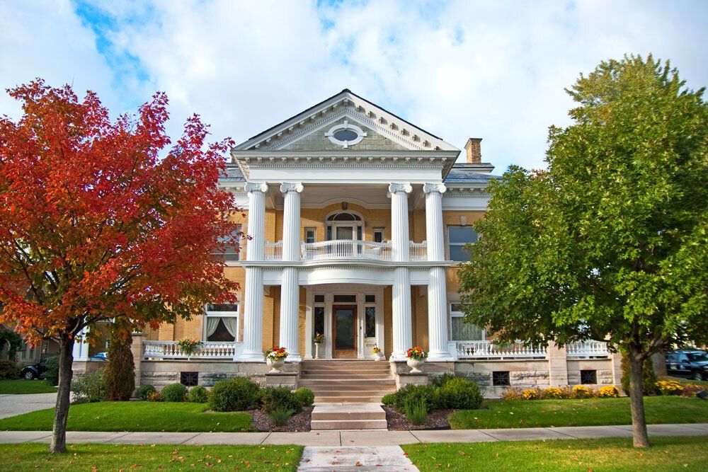 a large house with a porch and trees in front of it