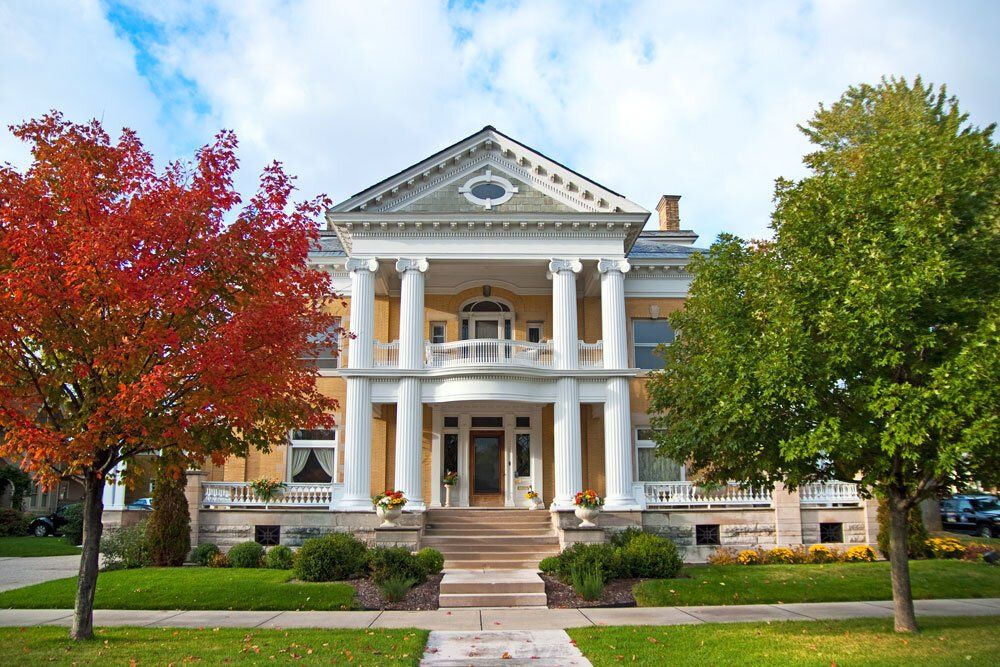 a large house with a porch and trees in front of it