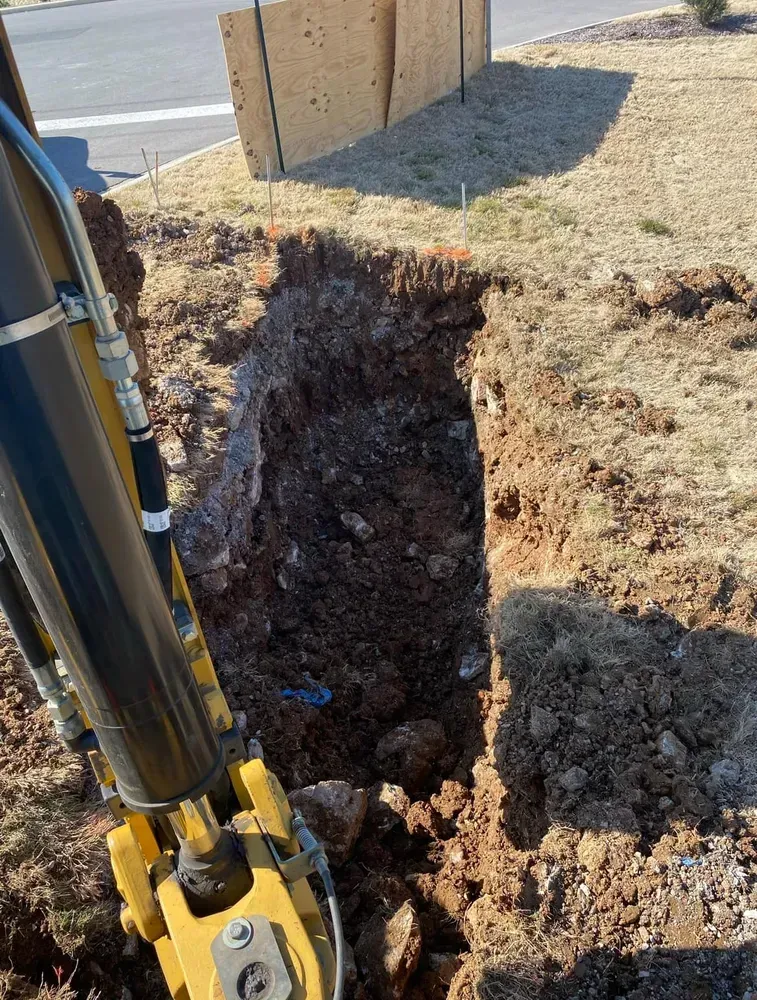 A yellow excavator is digging a hole in the ground.