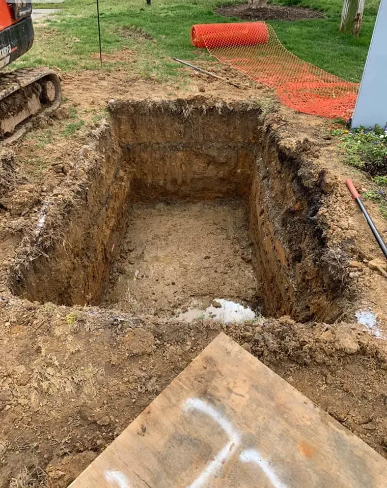 A large hole in the ground is being filled with dirt.