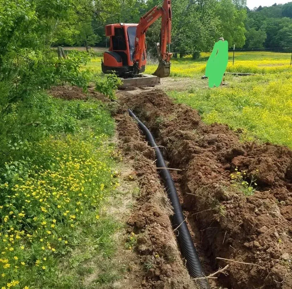 An orange excavator is digging a hole in a field