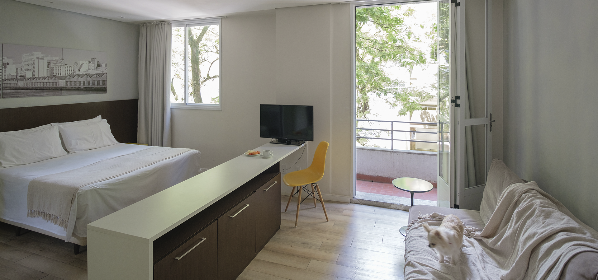 Um quarto de hotel com cama, sofá, mesa e televisão.