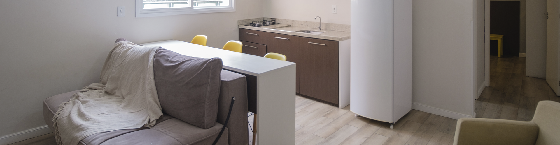 Uma sala com sofá, mesa e geladeira.