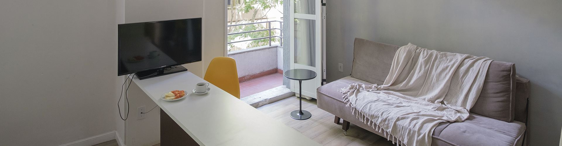 Uma sala de estar com sofá, mesa e televisão.