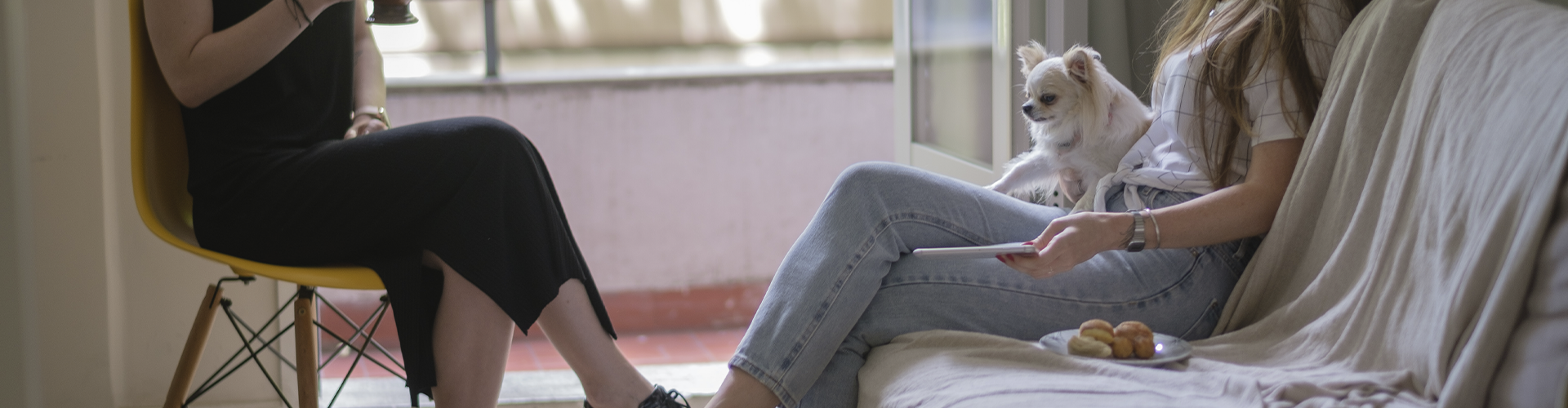 Duas mulheres estão sentadas em um sofá com um cachorro.