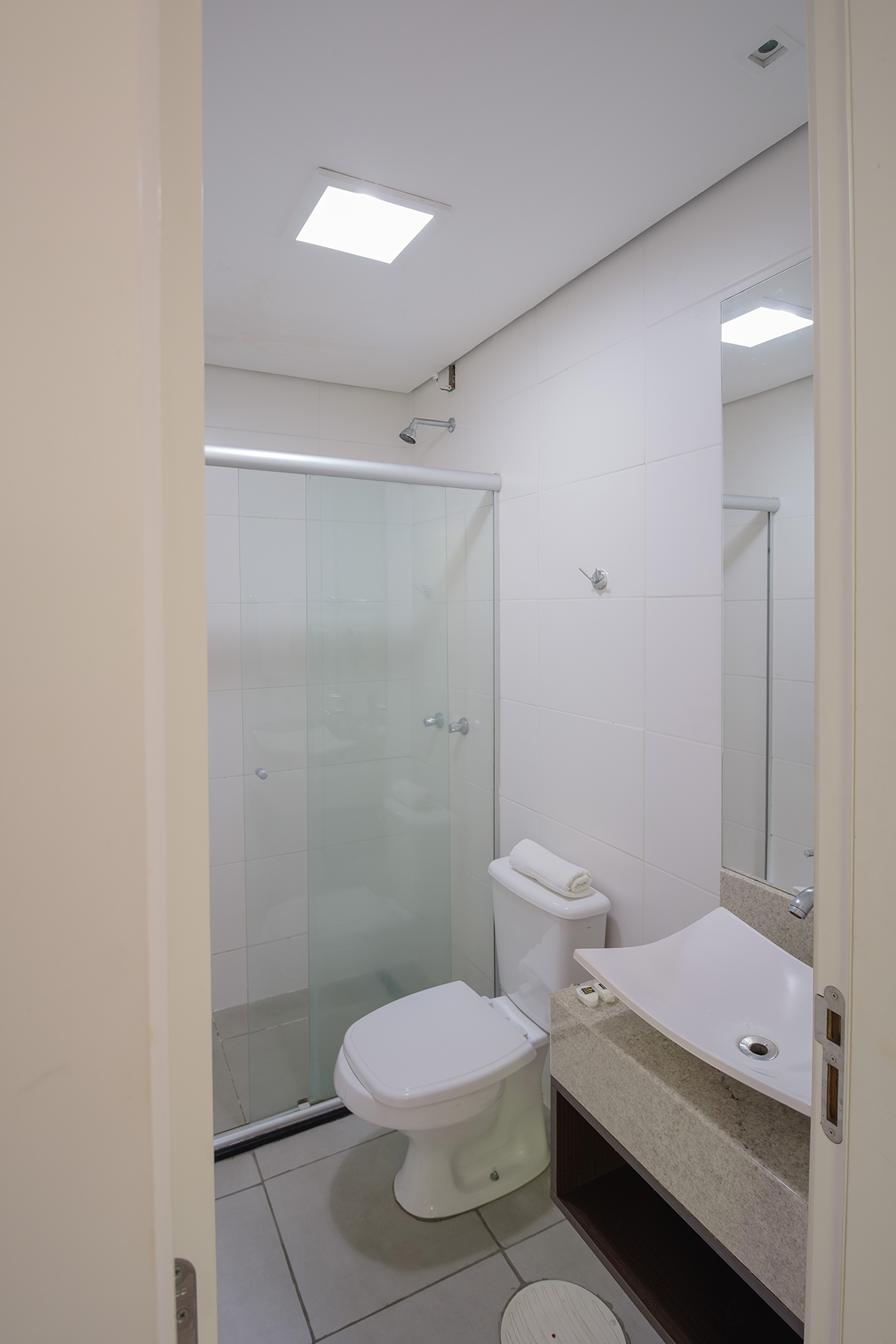 Um banheiro com vaso sanitário, pia, chuveiro e espelho.