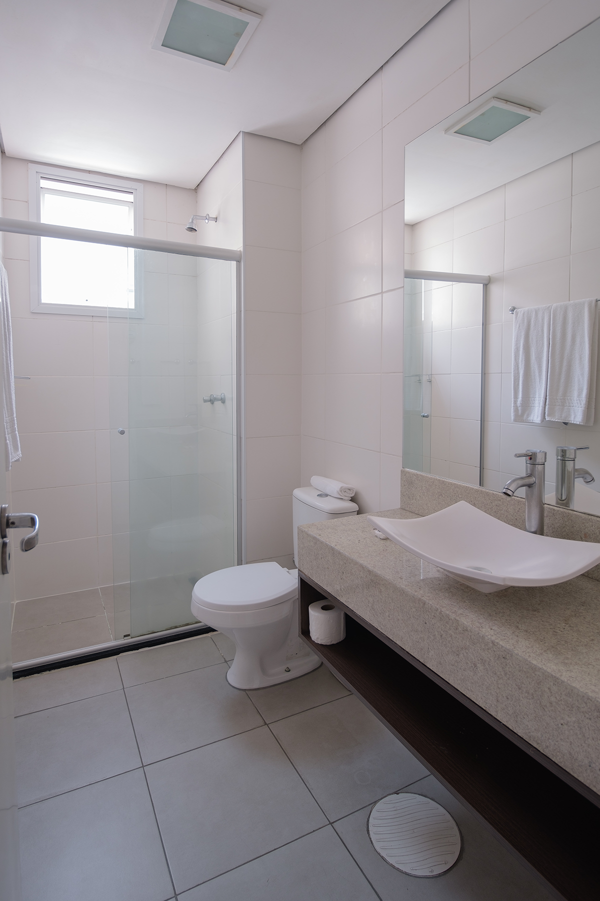 Um banheiro com vaso sanitário, pia, chuveiro e espelho.