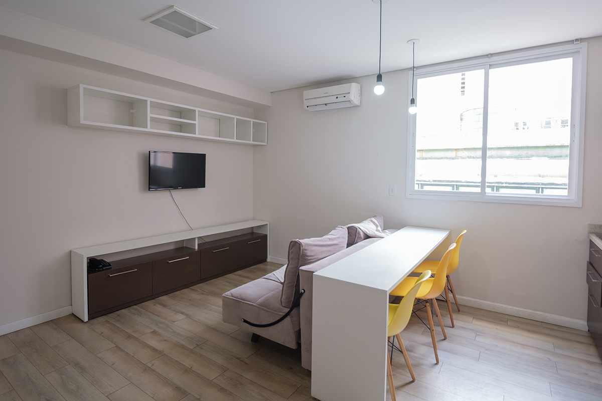 Uma sala com sofá, mesa, cadeiras e televisão.