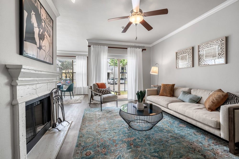 a living room with a couch, fireplace, coffee table, and ceiling fan at Marquis at Lantana in Flower Mound, TX.