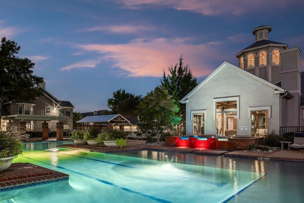 a large swimming pool with a building in the background at night at Marquis at Lantana in Flower Mound, TX.