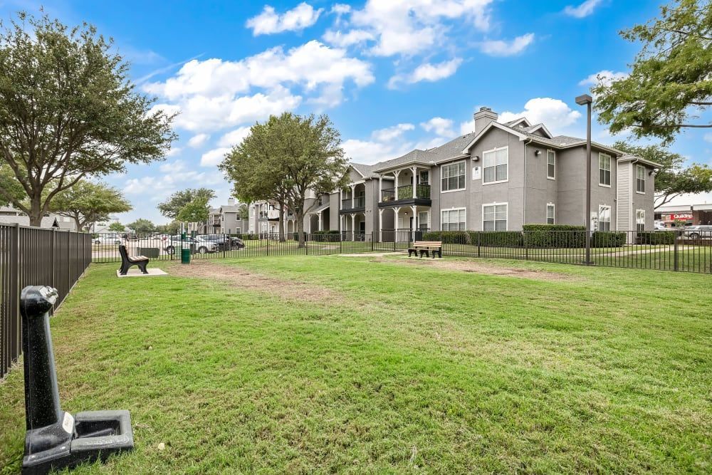 a large grassy field with a fence and a building in the background at Marquis at Lantana in Flower Mound, TX.