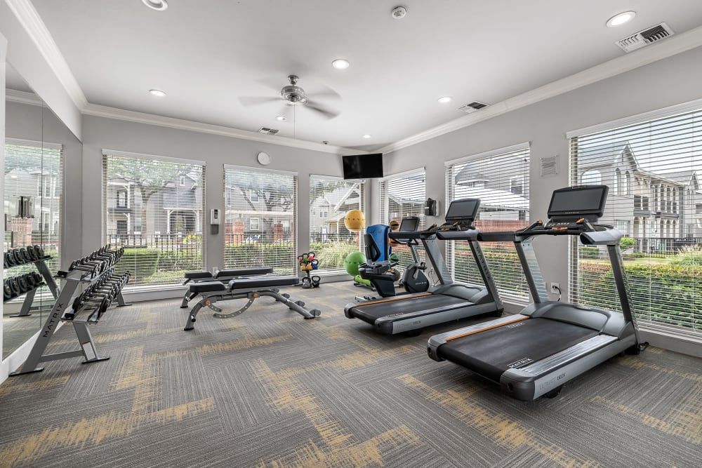 a gym with treadmills, dumbbells, and a ceiling fan at Marquis at Lantana in Flower Mound, TX.