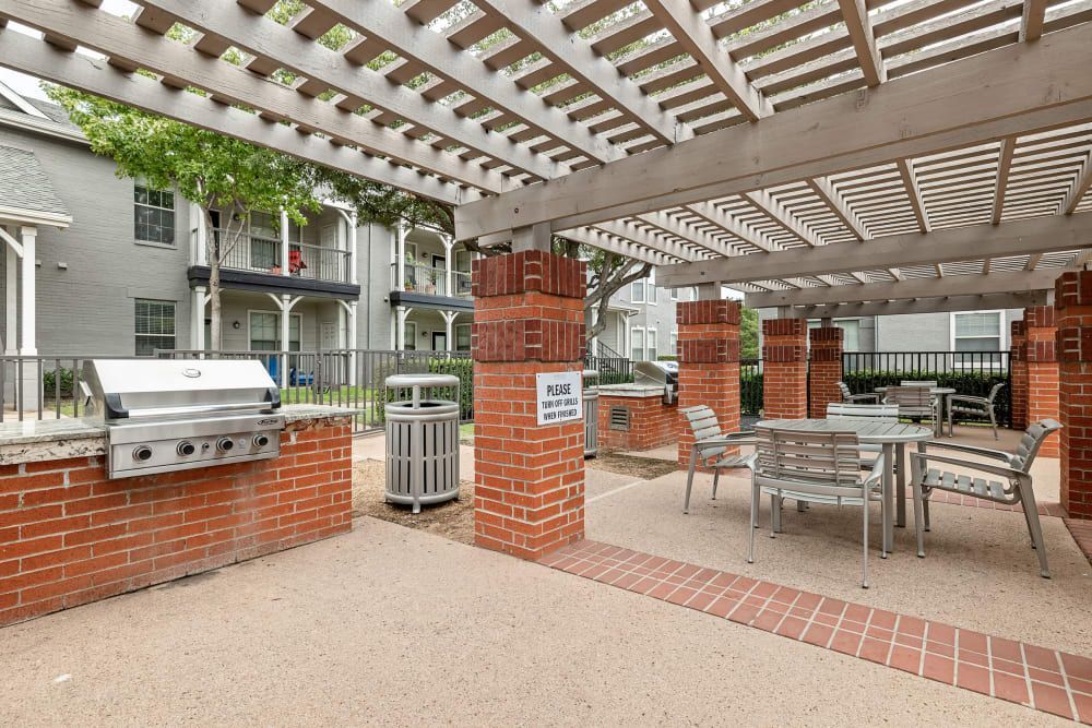 a grill and a table under a pergola at Marquis at Lantana in Flower Mound, TX.