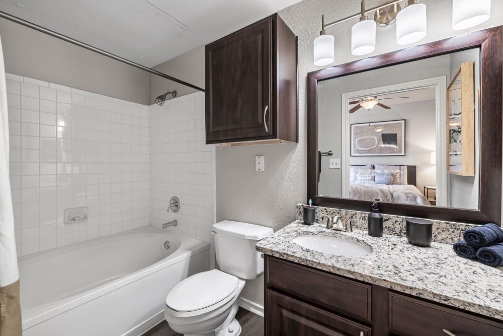 a bathroom with a toilet, sink, bathtub, and mirror at Marquis at Lantana in Flower Mound, TX.
