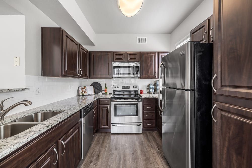 a kitchen with stainless steel appliances and wooden cabinets at Marquis at Lantana in Flower Mound, TX.